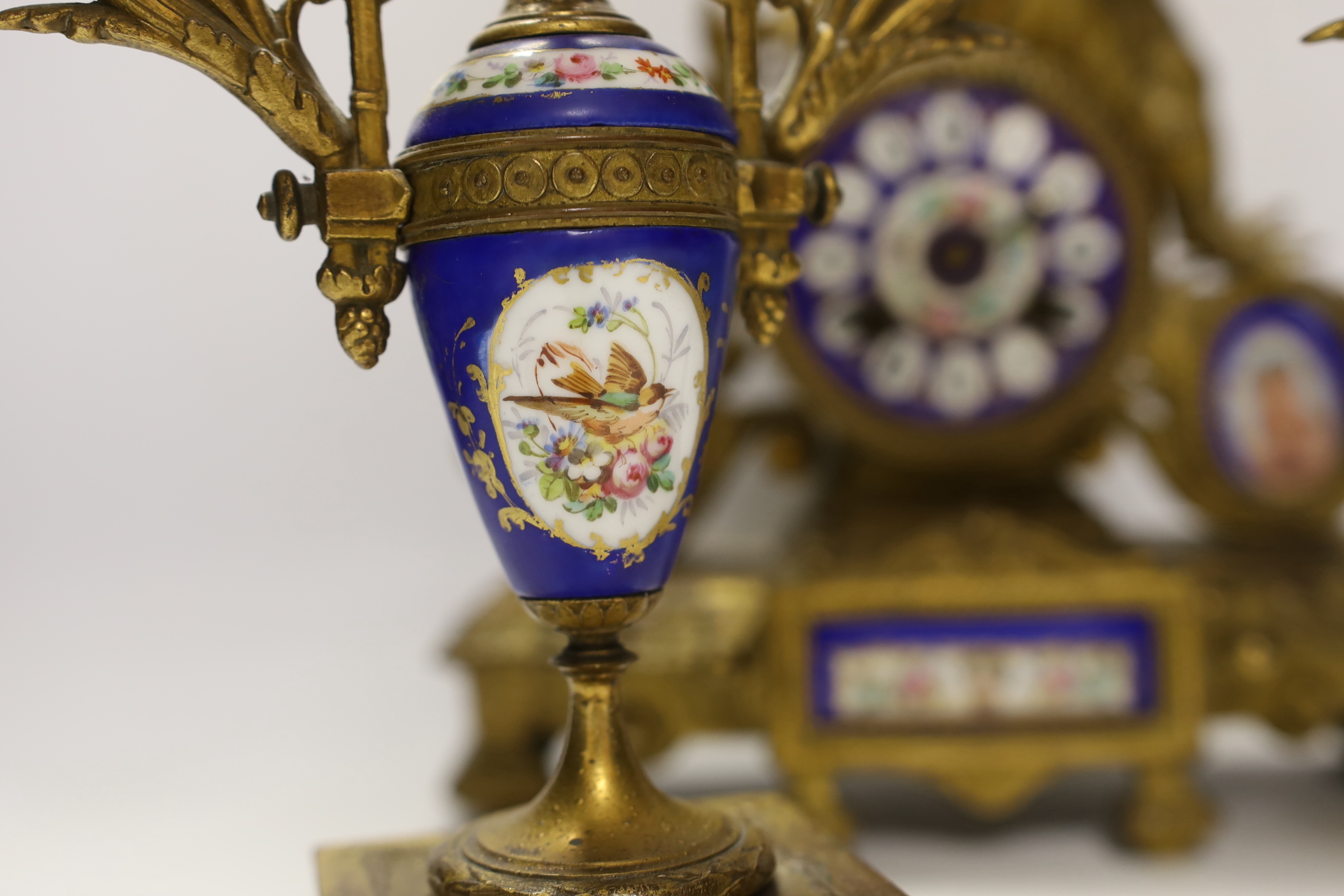 A 19th century ornate French gilt brass and porcelain clock, with two matching two branch candelabra garnitures, clock 31cm high